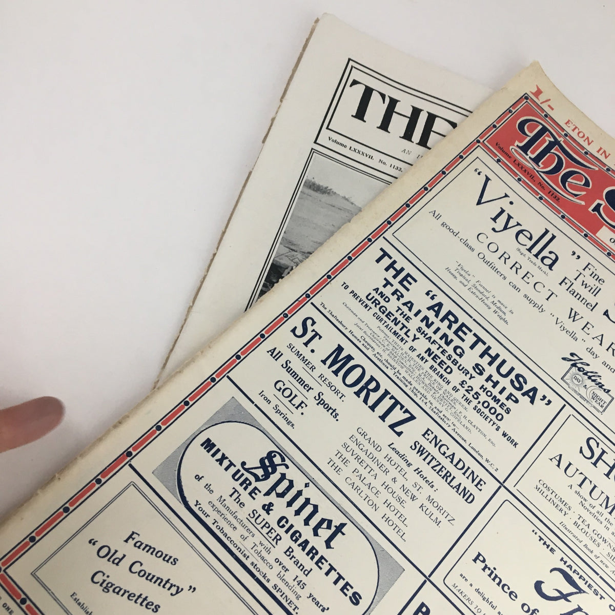 Close-up view of The Sphere Newspaper dated October 1, 1921, showing advertisements for the Aretusa training ship and St. Moritz vacations, highlighting its historical context and vintage appeal.
