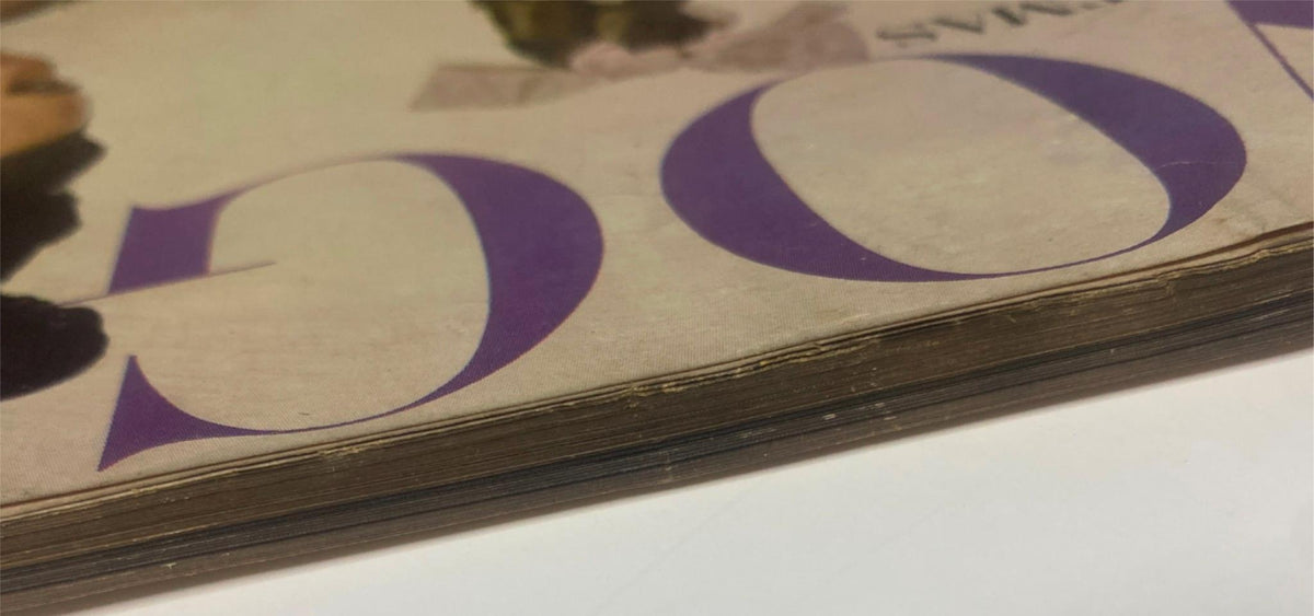 Side view of the cover of Vogue Magazine December 1962, highlighting the iconic purple lettering and age-related yellowing at the edges.