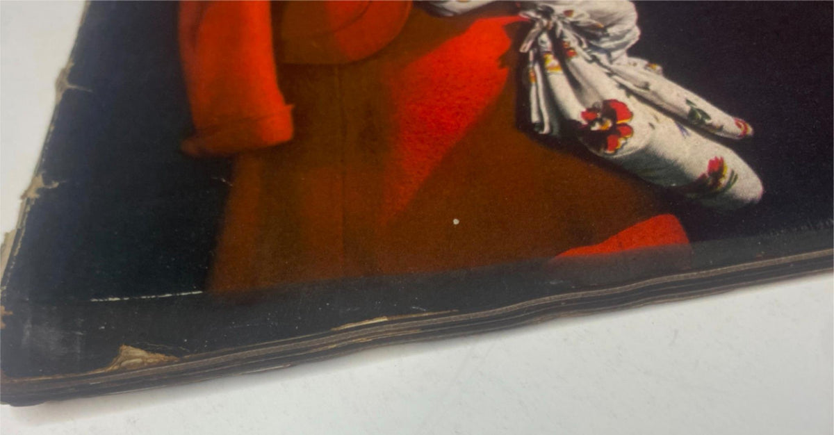 Close-up of the edge of Vogue Magazine January 1, 1942 Sandy Rice Cover by John Rawlings, showcasing slight wear with a vibrant red garment and floral details in the background.