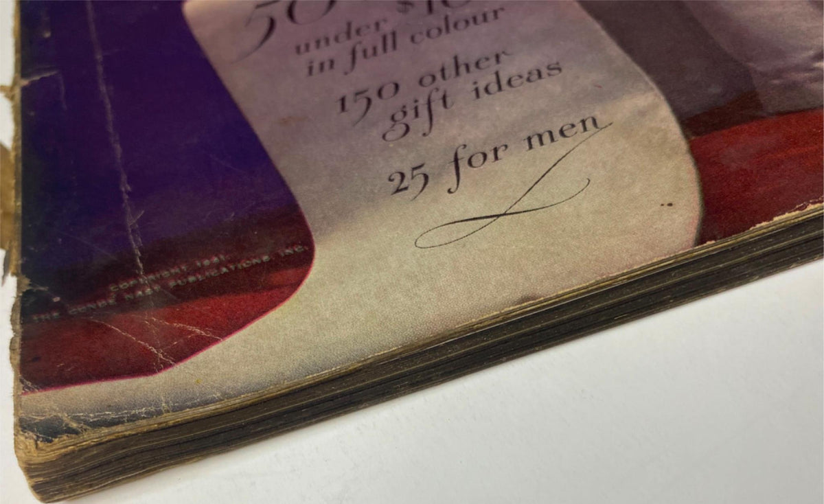 Close-up view of the side edge of Vogue Magazine December 1, 1941 Betty McLauchlen Cover by John Rawlings, showcasing the worn spine and colored gift ideas on the cover, indicative of its vintage condition.