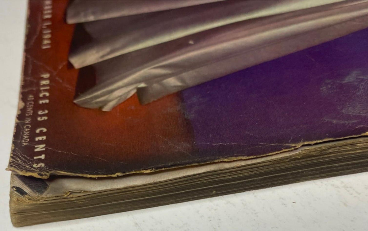 Detailed view of the bottom edge of Vogue Magazine December 1, 1941 Betty McLauchlen Cover by John Rawlings, highlighting the aged pages and colorful cover design, suggestive of the magazine's historic significance.