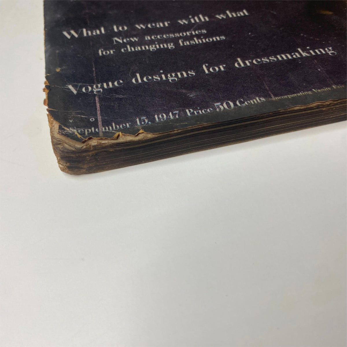 Close-up view of the spine of Vogue Magazine September 15, 1947, showing wear and tear typical of vintage magazines, emphasizing its historical significance.