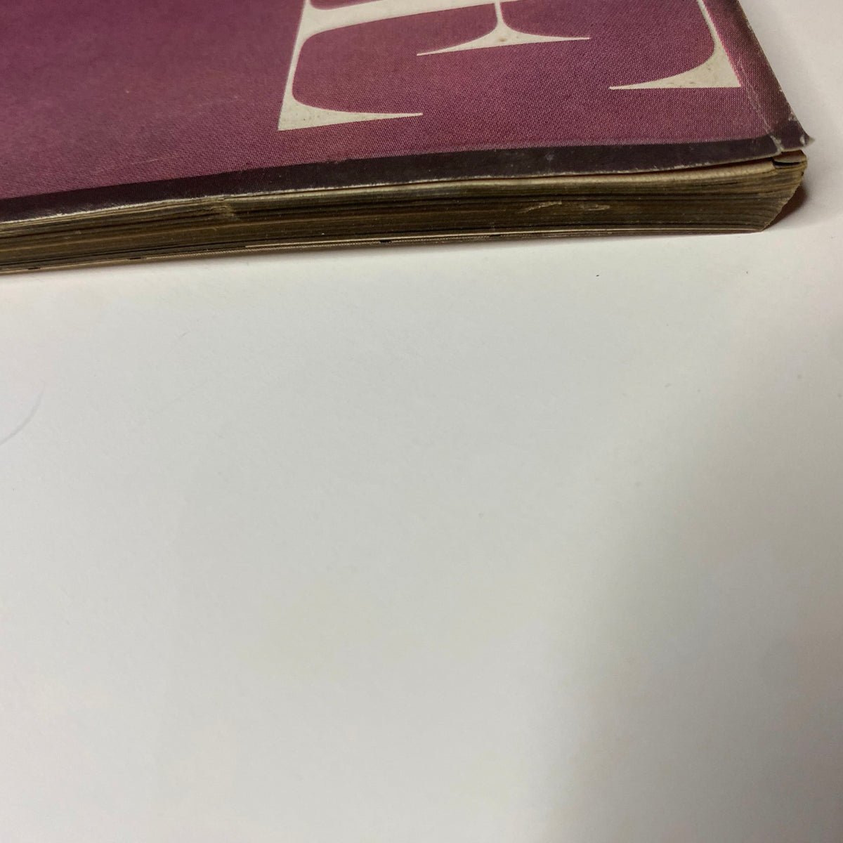 Detailed view of the spine of Vogue Magazine August 15, 1957, showcasing the magazine's vintage wear and the era's stylistic elements.