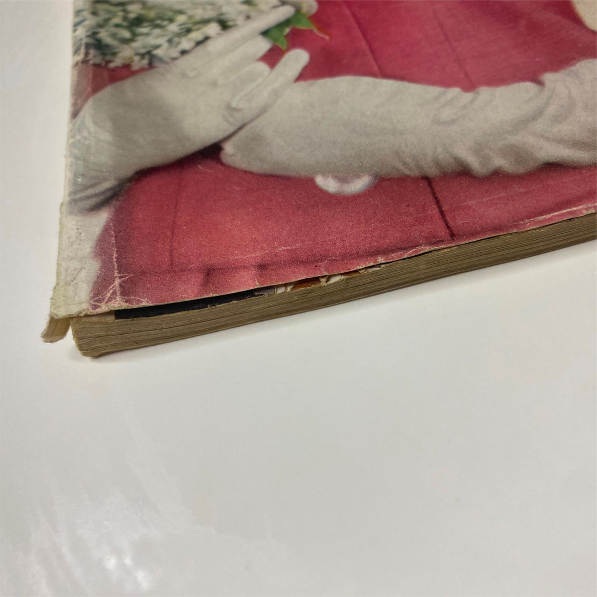 Close-up of the spine and bottom edge of Vogue Magazine April 1, 1960, illustrating the magazine's vintage condition and wear from storage.