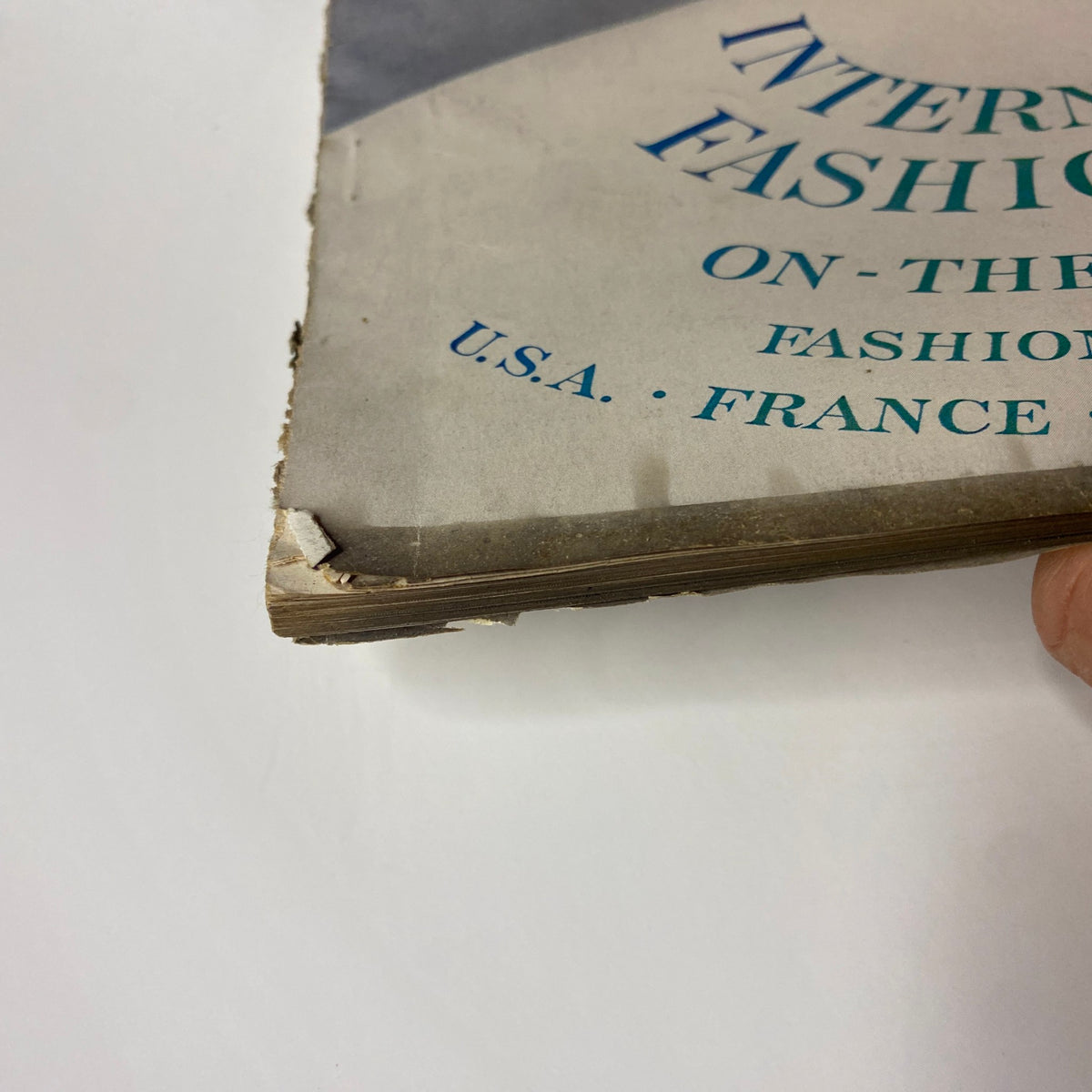 Close-up of magazine spine detail featuring 'International Fashion' from the March 15, 1954 Vogue Magazine, illustrating the magazine's wear and vintage characteristics.