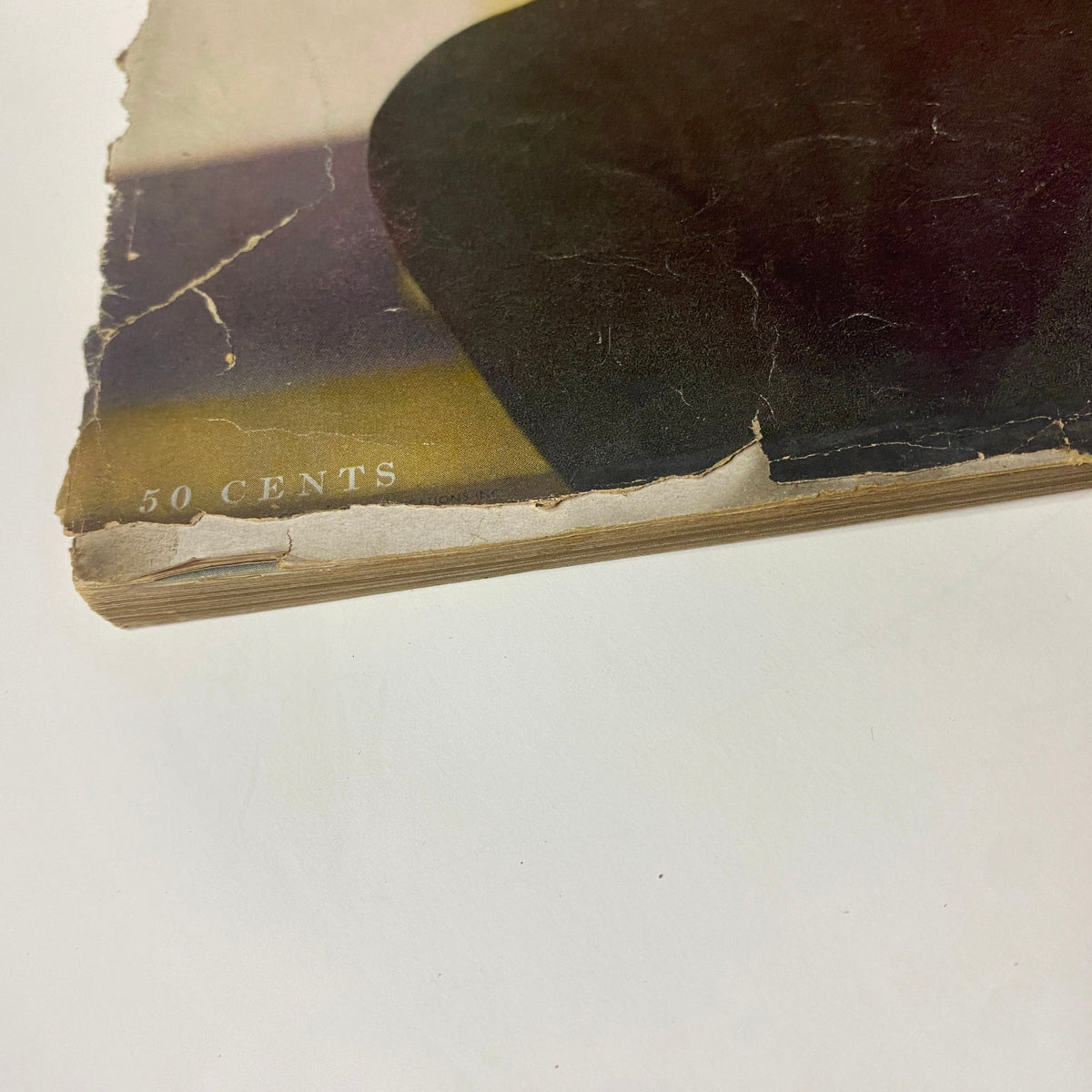 Close-up of the edge of the Vogue Magazine November 15, 1954 showing signs of aging with visible creases and a price tag of '50 cents', highlighting the magazine's nostalgic value as a vintage fashion publication.