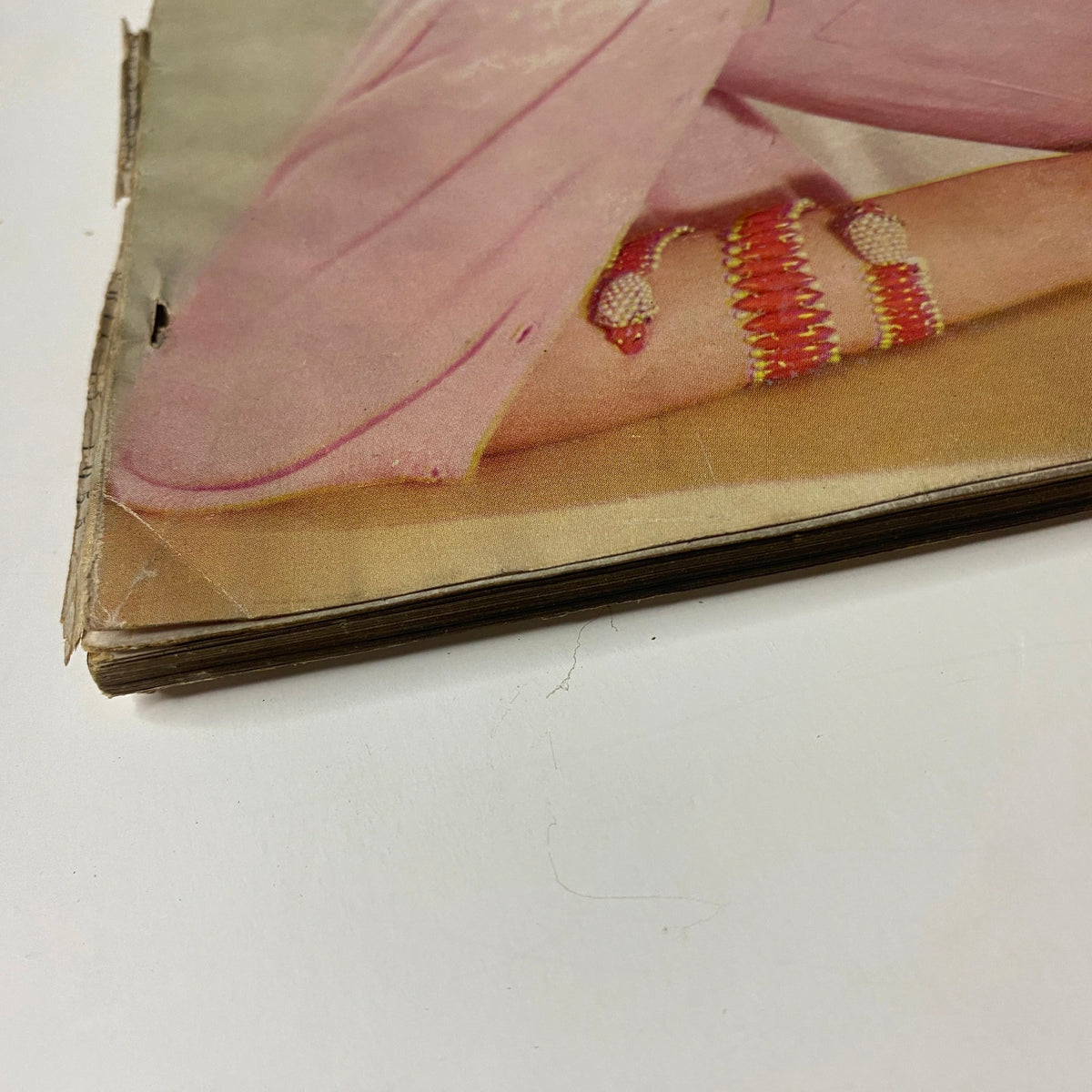 Close-up image of Vogue Magazine April 15, 1955 showing a vintage dress detail with jewelry, highlighting wear and age.