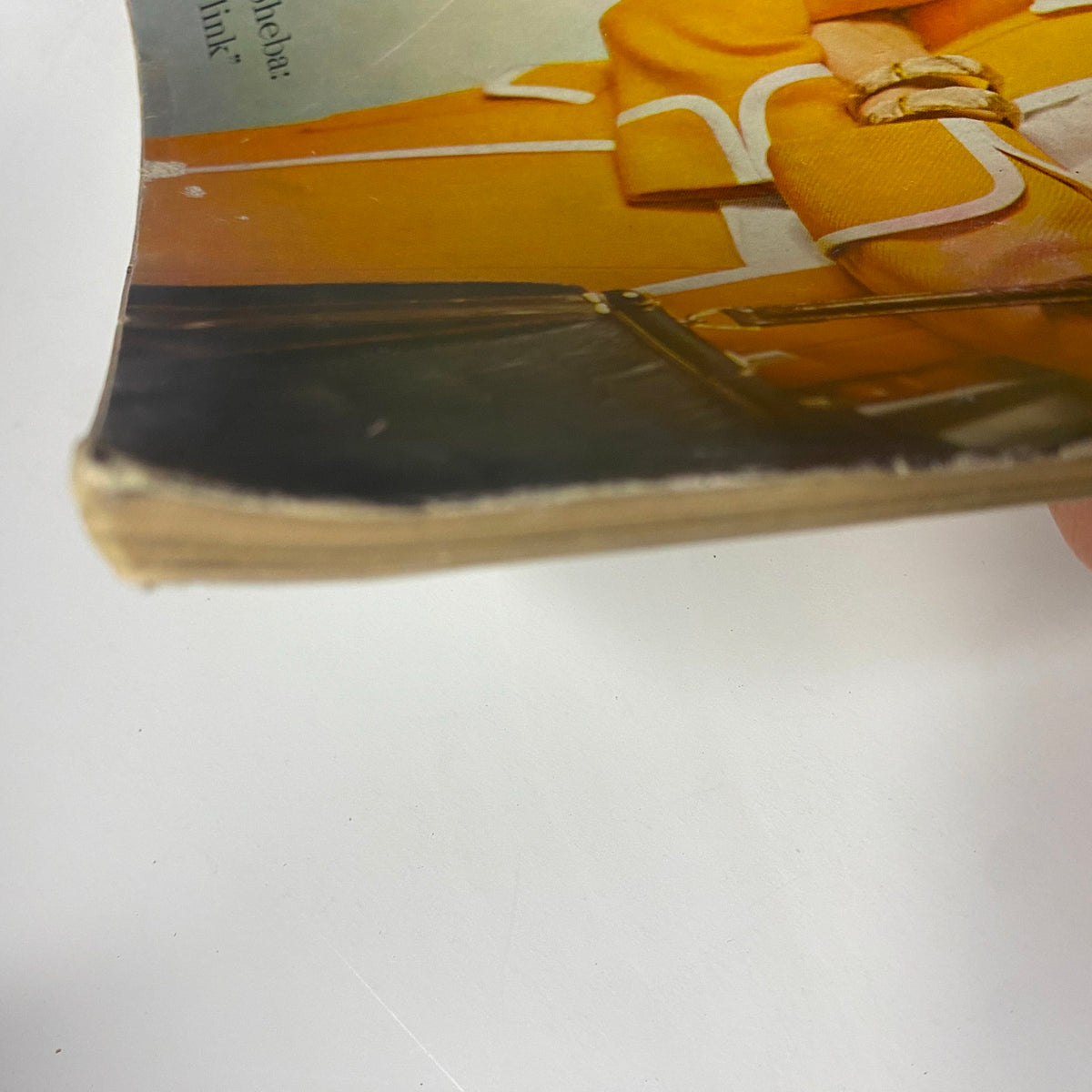 Close-up view of the edge of Vogue Magazine March 15, 1960, detailing wear with torn paper and a vibrant yellow ribbon motif from the cover.