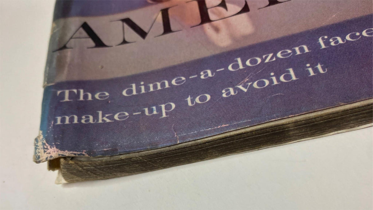Close-up image of the edge of Vogue Magazine February 1, 1961 revealing wear and tear, with a focus on the text discussing makeup, reflecting the magazine's vintage qualities.