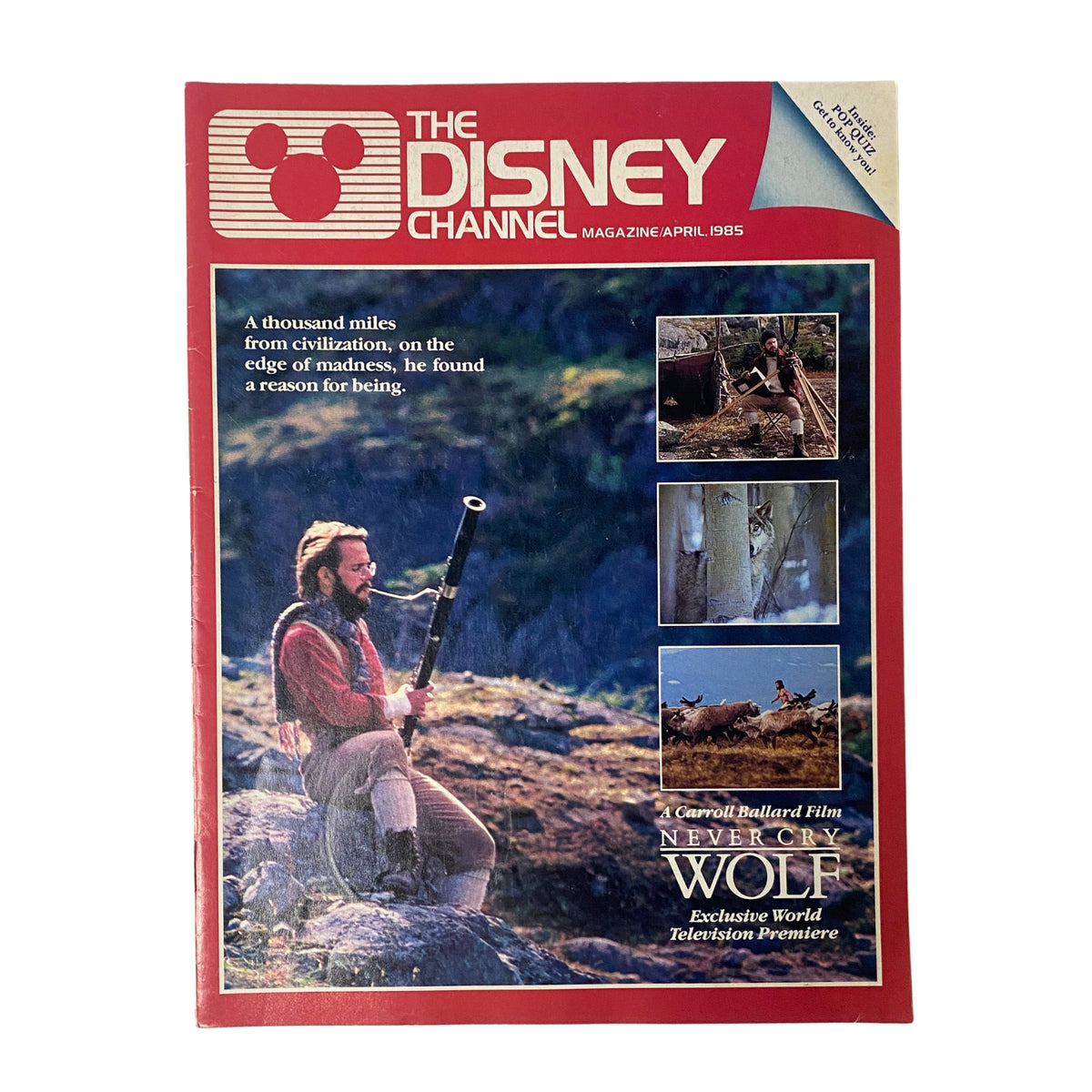 Cover of The Disney Channel Magazine, April 1985 featuring a Carroll Ballard Film 'Never Cry Wolf'. The cover displays a man in a natural setting with a rifle, complemented by images from the film and a striking red and blue design.