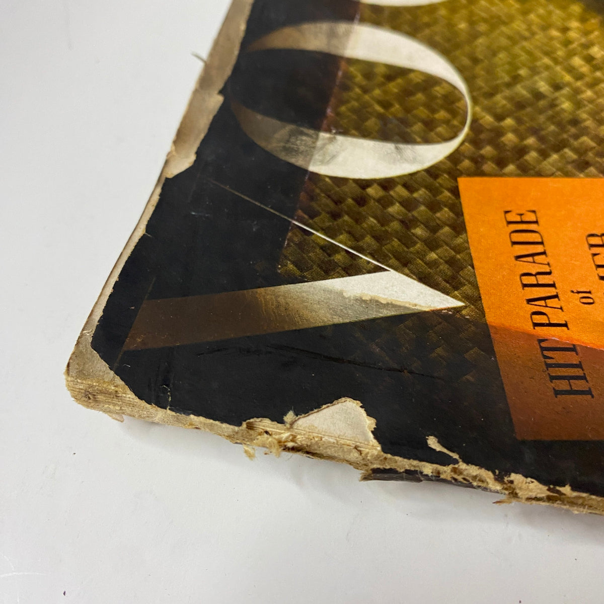 Close-up of the corner of Vogue Magazine June 1, 1943 revealing wear and tear on the cover, with a focus on the title and the vibrant 'Hit Parade of Summer Clothes' ad.
