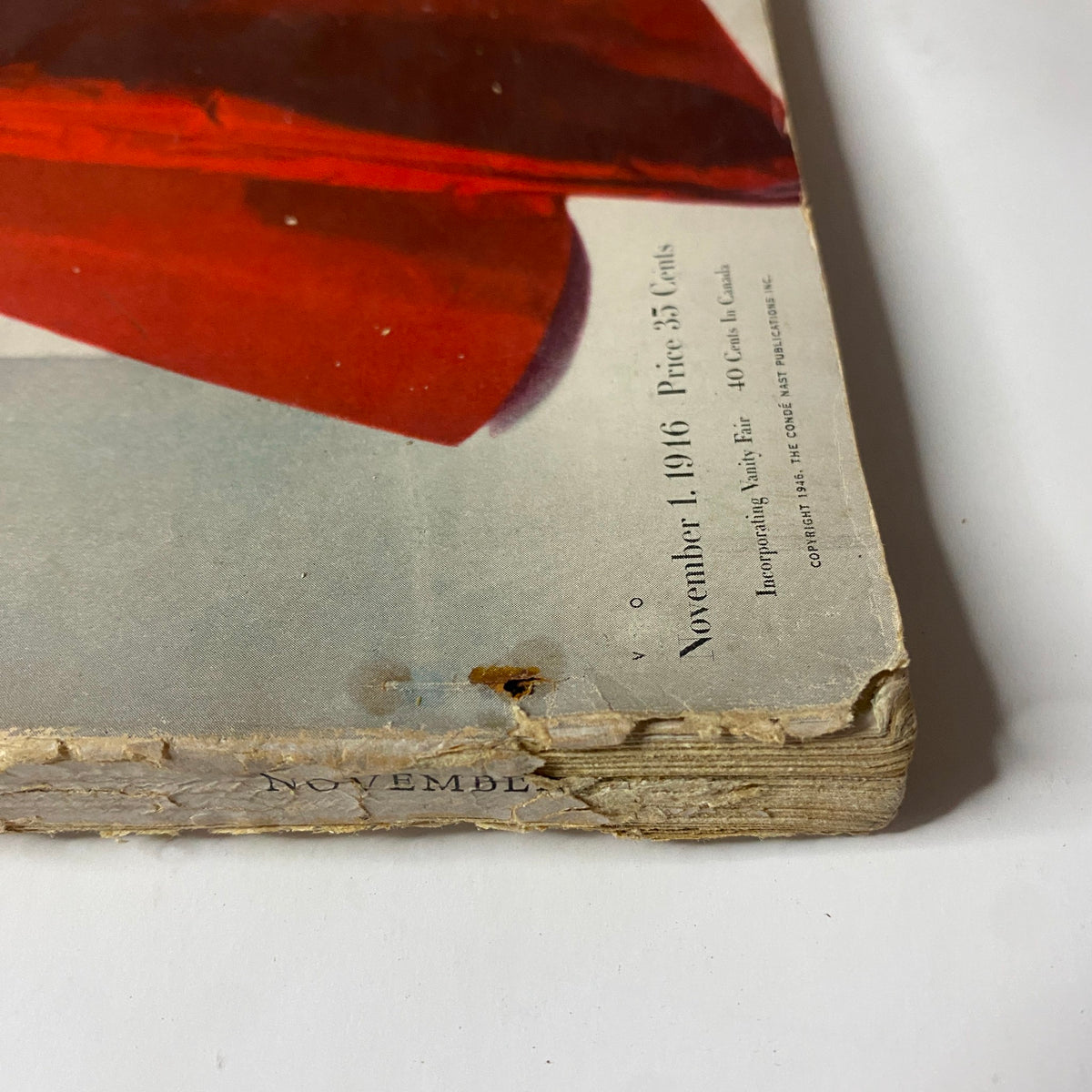 Detailed view of the bottom edge of Vogue Magazine November 1, 1946 showing wear and tear, featuring a red garment on the cover, emphasizing styles for three generations.