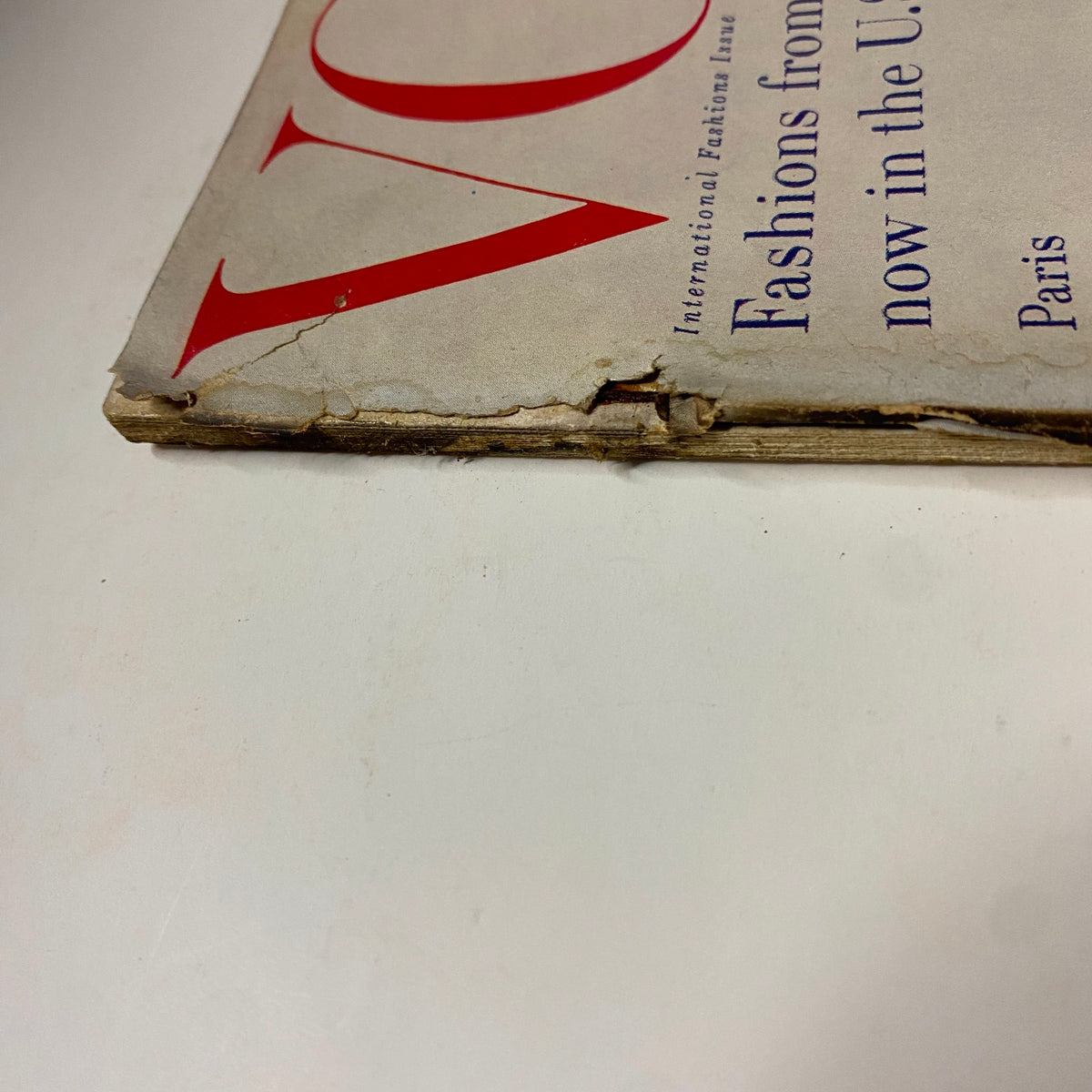 Close-up view of the spine of the March 15, 1955 Vogue Magazine, indicating wear and tear consistent with its vintage status.