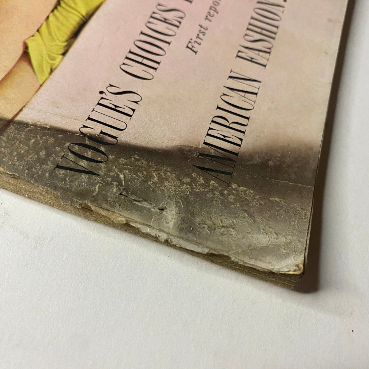 Side view of the bottom edge of Vogue Magazine March 1, 1954 showing wear and tear, with a focus on the corner damage. The cover displays Mary Jane Russell and Cherry Nelms and emphasizes American fashion accessories.