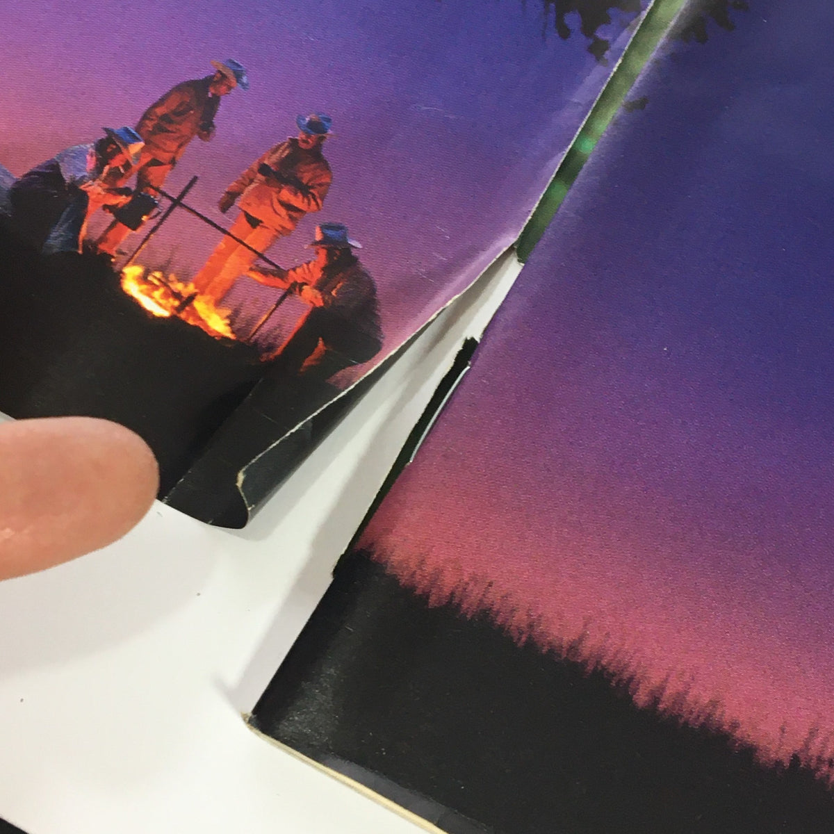 Close-up of the interior pages of Motor Cyclist Magazine March 1997 highlighting minor damage at the edges with a smoky sunset illustration.