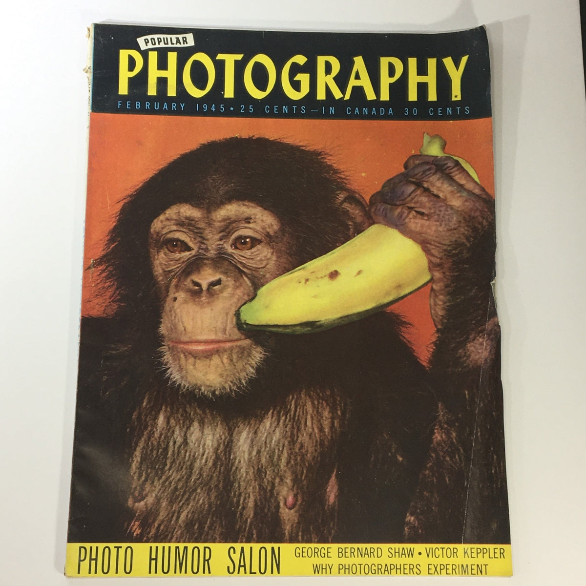 Cover of the VTG Popular Photography Magazine, February 1945, showcasing a chimpanzee holding a banana. This collectible issue features George Bernard Shaw and delves into the evolving art of photography.
