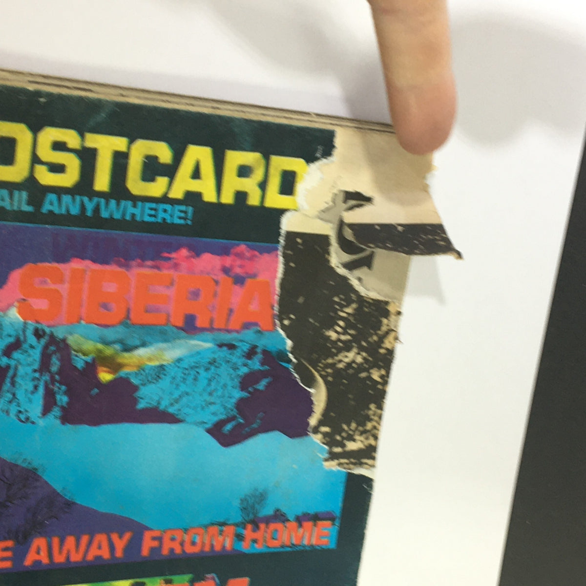 Close-up view of the top edge of Stan Lee's Crazy Magazine January 1977 issue #22, showing minor damage and wear with a focus on the illustration and colorful postcard design featuring Siberia. Perfect for collectors interested in vintage comic magazines.