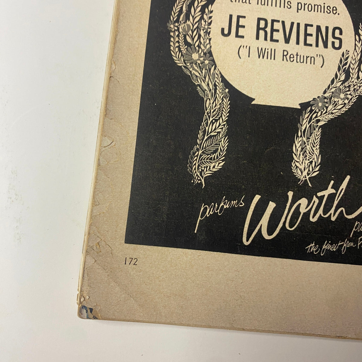A close-up of an advertisement from Vogue Magazine October 15, 1960 showcasing the perfume 'Je Reviens' ('I Will Return') with elegant lettering and a woman's illustration.