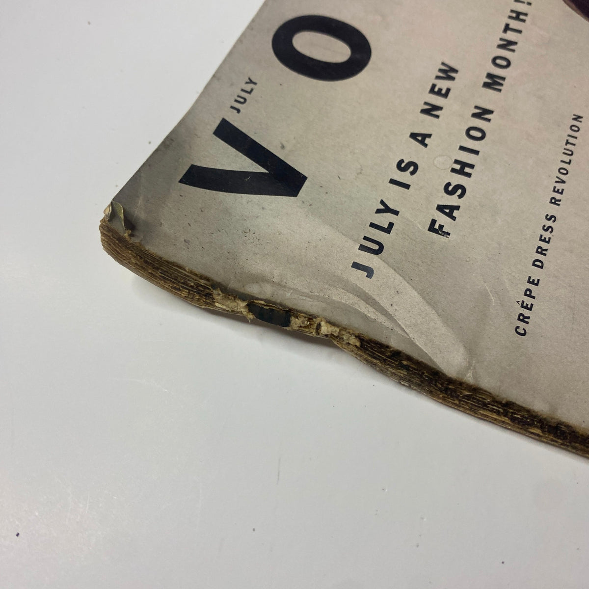 Close-up view of the damaged spine of Vogue Magazine July 1952, featuring Ruth Neumann cover by Irving Penn. Shows vintage wear and tear typical for historic magazines.