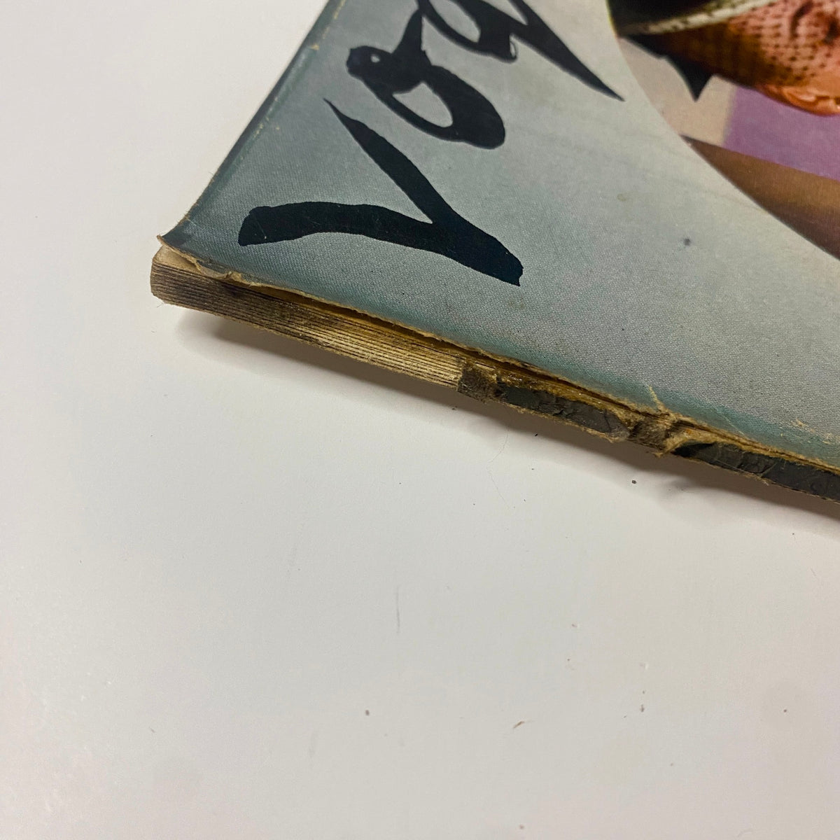 Close-up of the spine of Vogue Magazine August 1, 1942, with visible wear and tear. The title 'Vogue' can be seen clearly, reflecting its vintage status and condition.