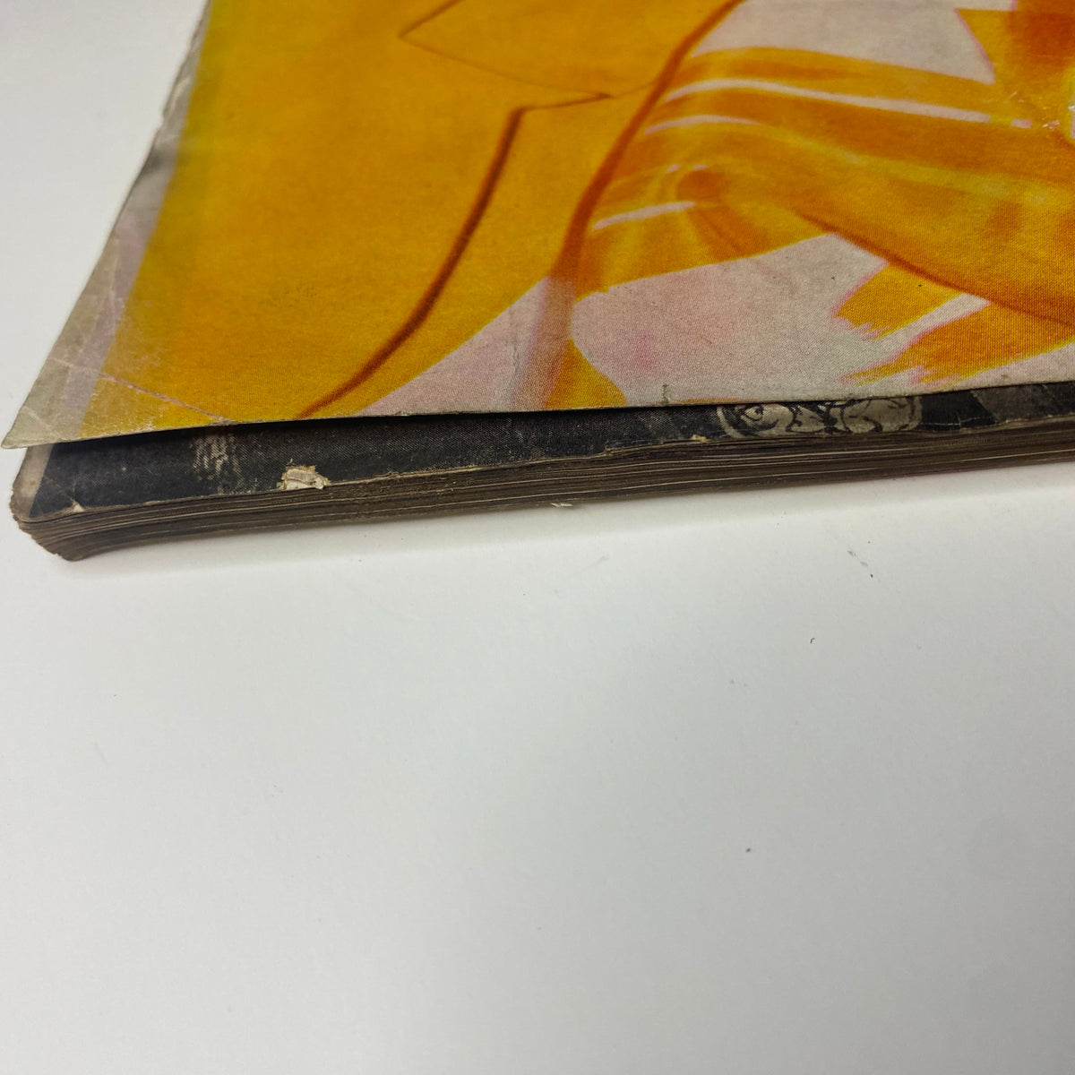 Detailed view of the bottom edge of Vogue Magazine January 1, 1961, highlighting the aged and worn paper characteristic of a vintage publication, featuring Dorothy McGowan Cover by Irving Penn.