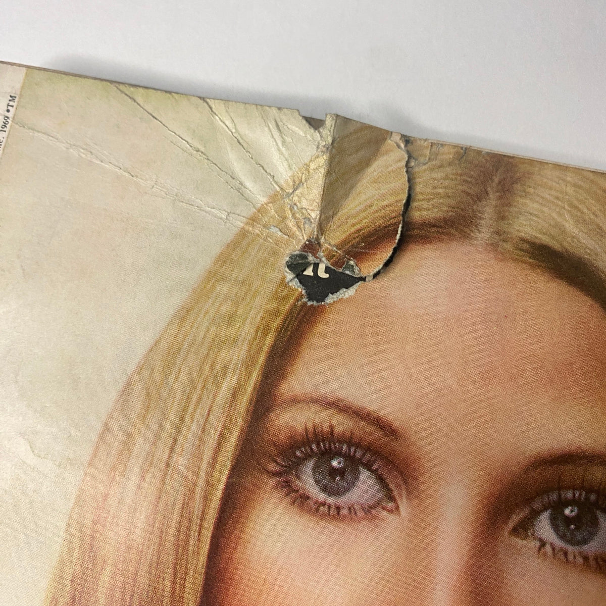 Damage on the top of Vogue Magazine February 15, 1969, showing a tear and crease on the cover, indicative of its age, while featuring the elegant gaze of a model.