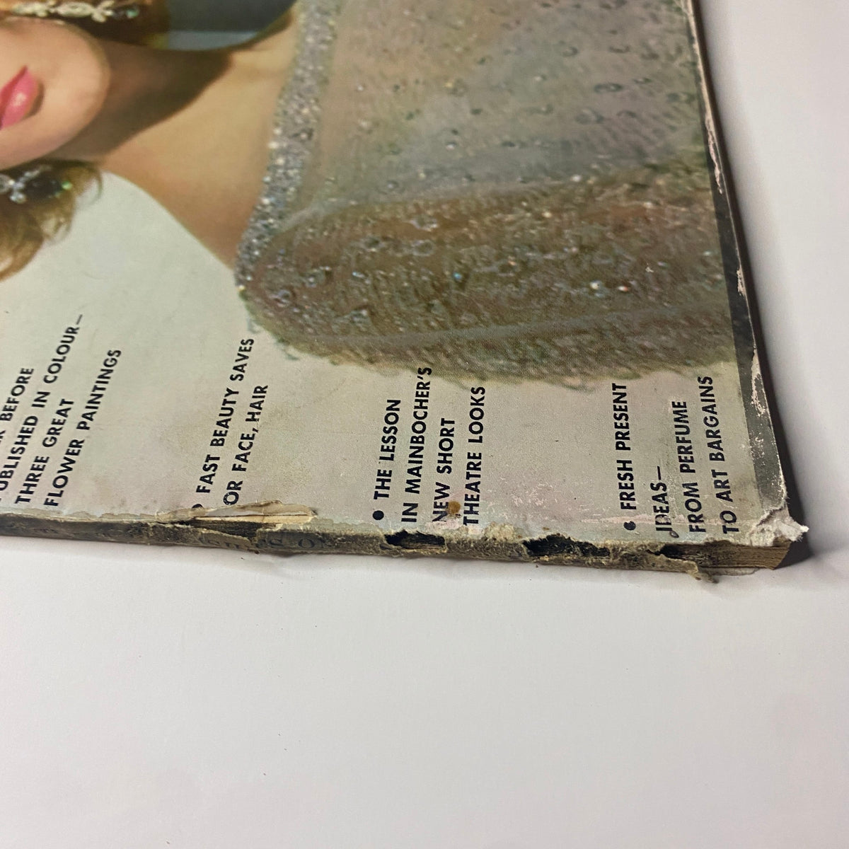 Close-up of the bottom edge of Vogue Magazine December 1961 Antonia Boekestyn Cover by Horst P. Horst, displaying vintage traits and slight wear on the cover.