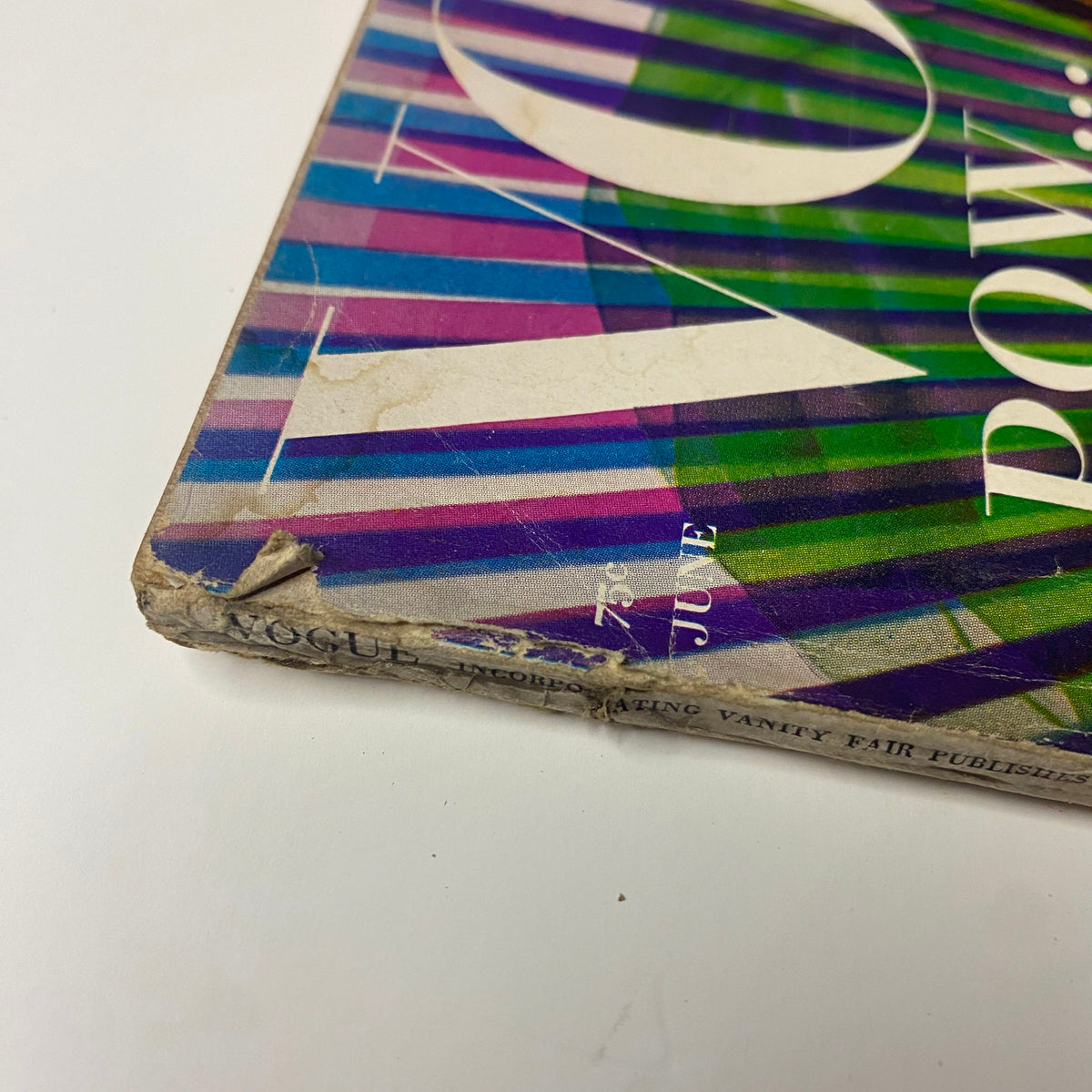 Close-up view of the edge of Vogue Magazine June 1965, highlighting wear and vintage characteristics while featuring the distinctive cover design.