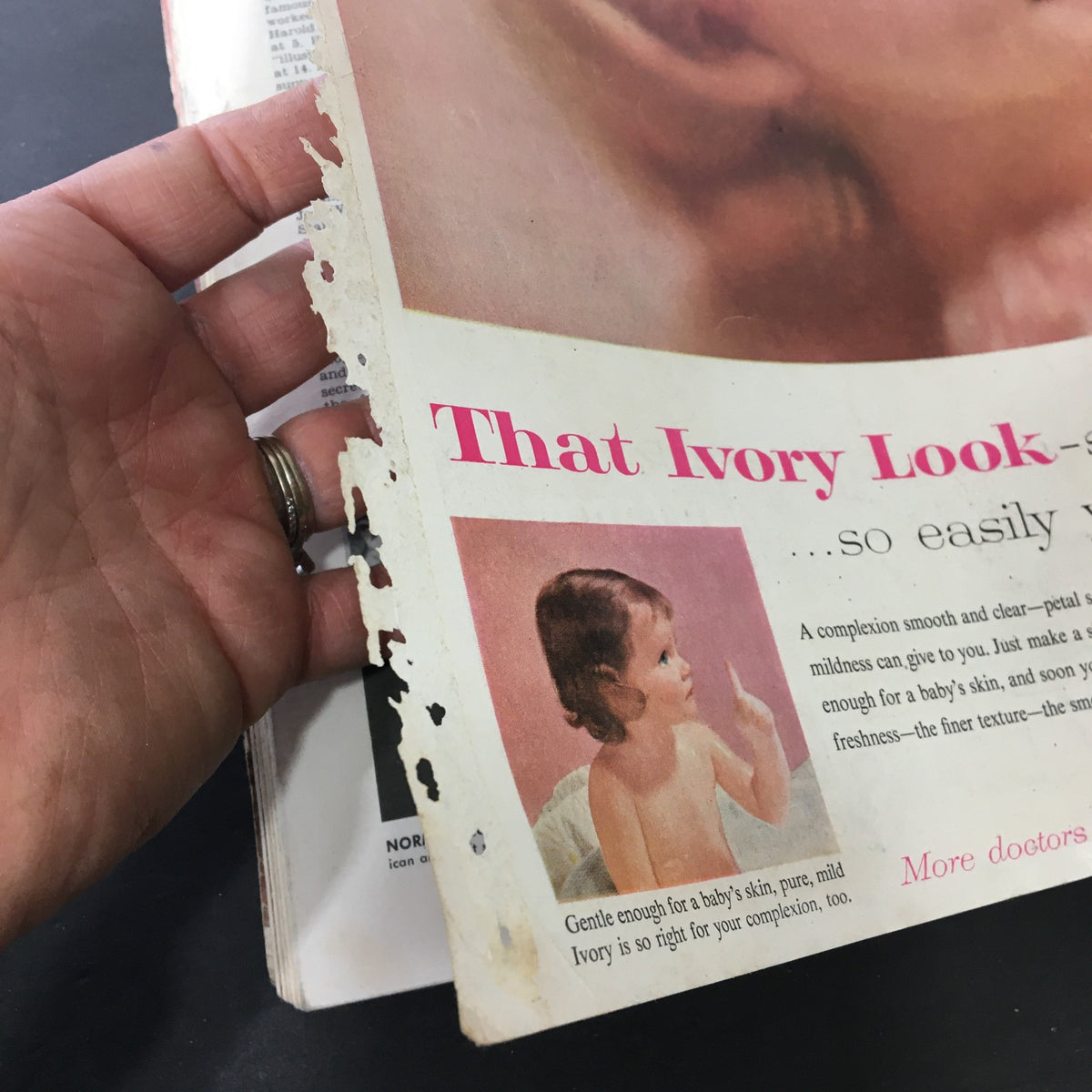 Close-up of a vintage magazine page from the VTG Journal Magazine July 1957 featuring a beauty advertisement titled 'That Ivory Look', showcasing a young child with a gentle expression. This image highlights the age-related wear, making it a unique piece of vintage memorabilia.