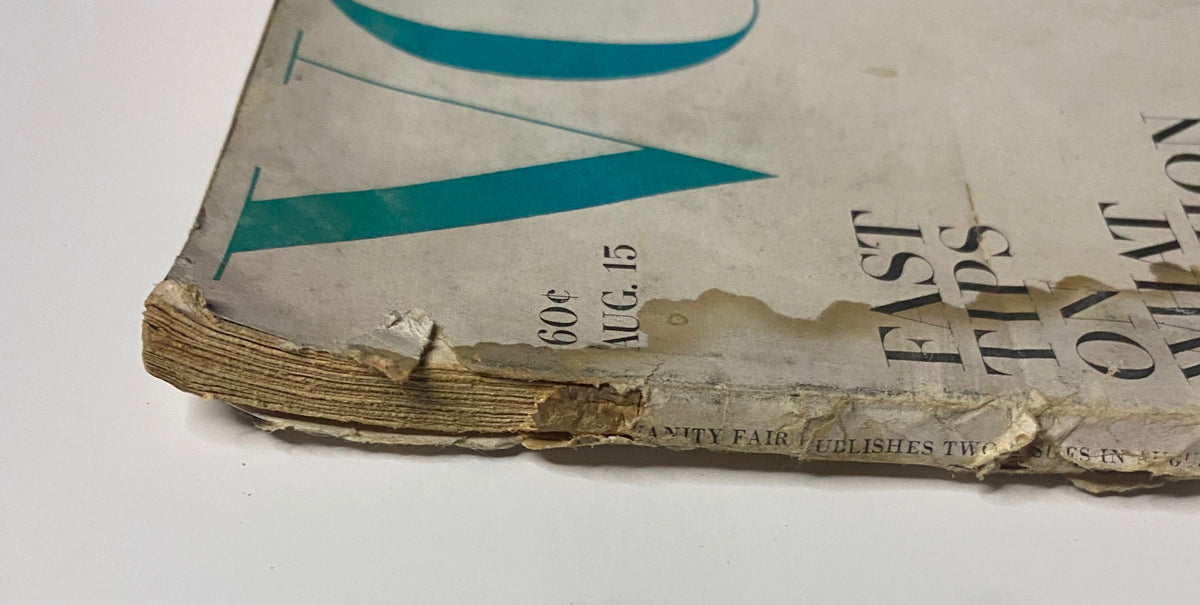 Close-up view of the worn spine of Vogue Magazine August 15, 1963, highlighting its vintage condition with visible wear and tear.