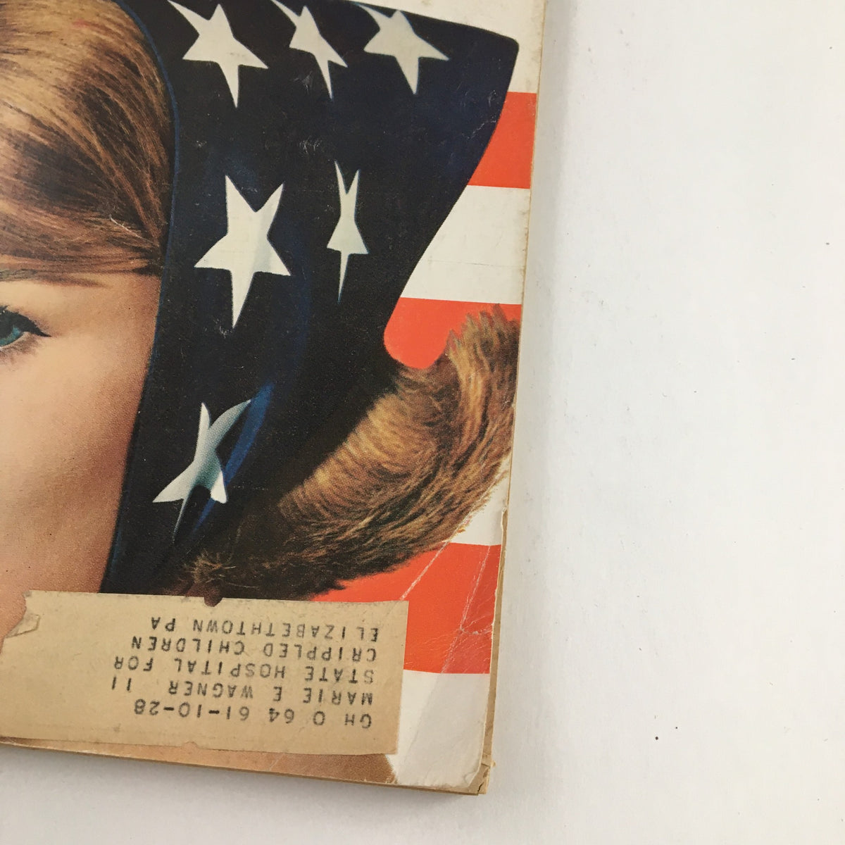 Close-up of the cover of Good Housekeeping Magazine July 1964 showcasing a model with a star-patterned head scarf and an address label.