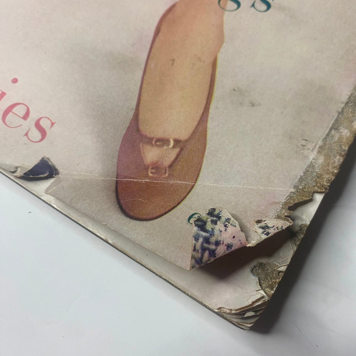 Close-up of the corner of Harper's Bazaar Magazine March 1955, highlighting minor wear and tear, with focus on the cover design featuring spring fashion items.