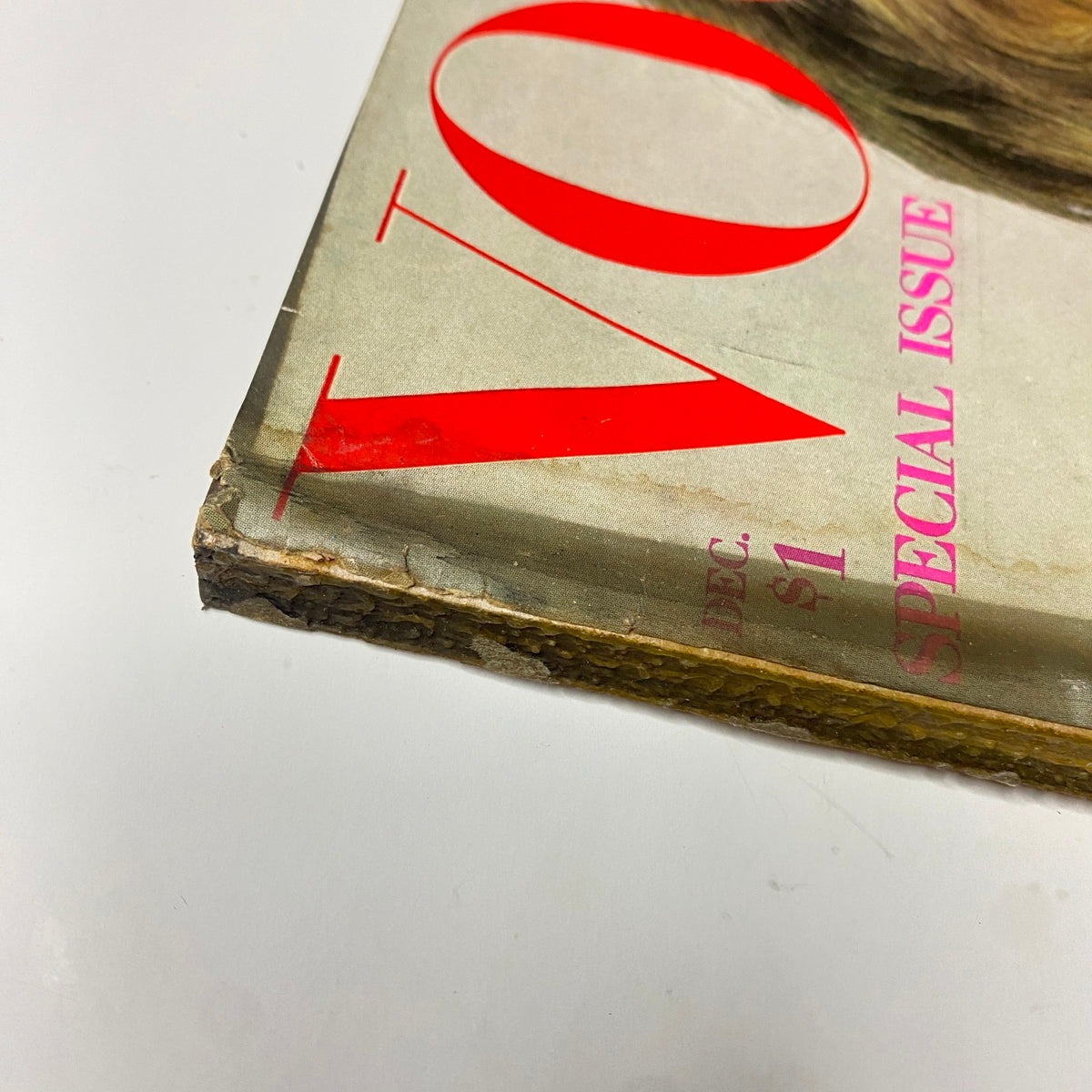 Detailed shot of the corner of Vogue Magazine December 1969 showing its worn edges and prominent red title 'VOGUE'. The cover presents a vintage design with hints of age-related wear.