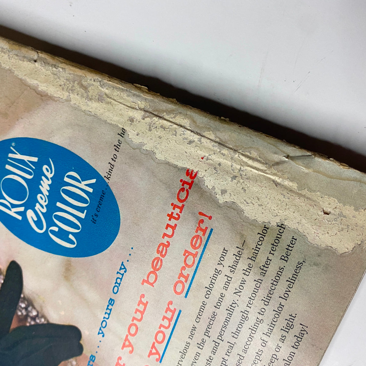 Close-up of the top edge of Harper's Bazaar Magazine April 1955, revealing damage and discoloration, highlighting the magazine's historical significance.