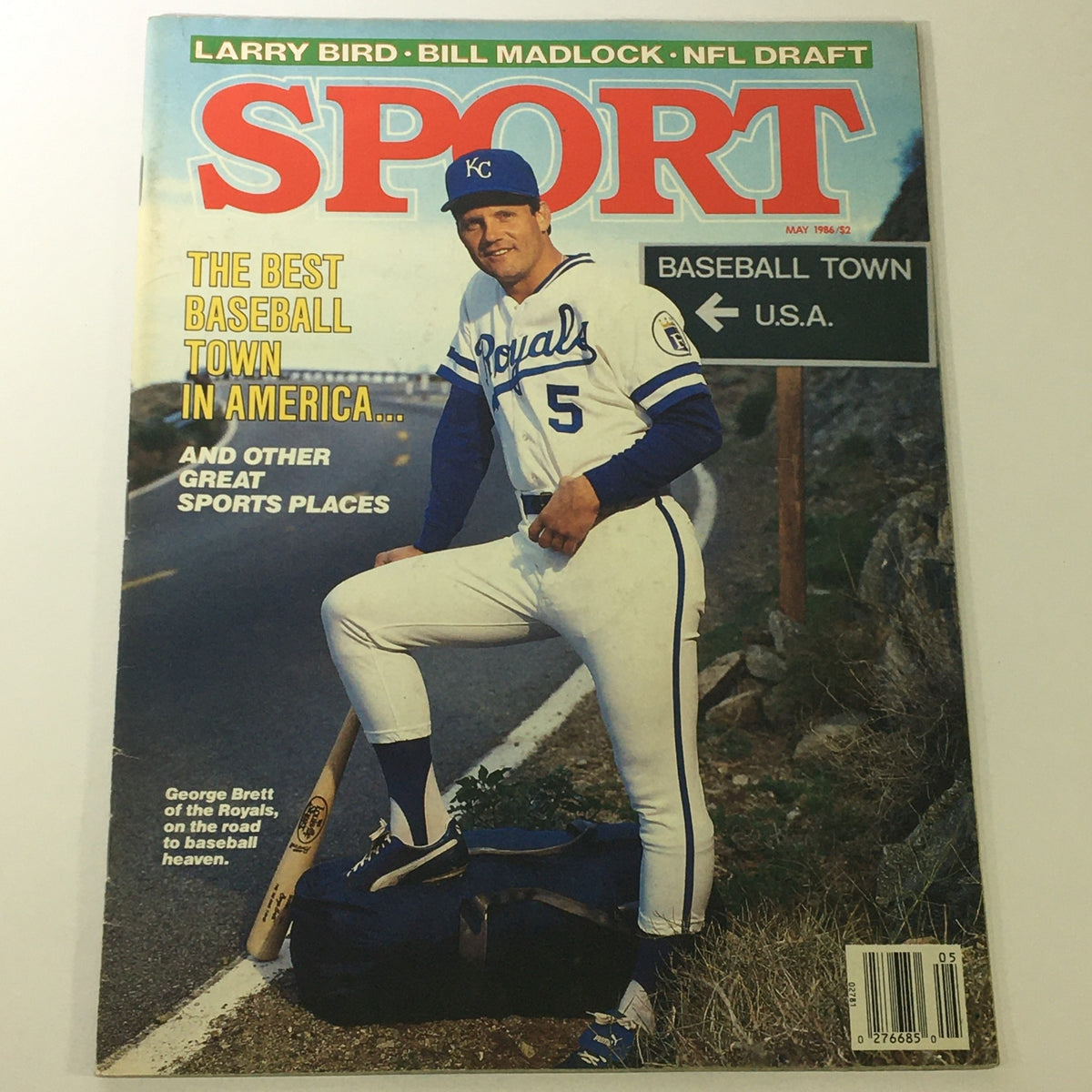 Cover of VTG Sport Magazine May 1986 featuring George Brett of the Kansas City Royals in a baseball uniform, posing with a bat next to a duffel bag, promoting the best baseball town in America.