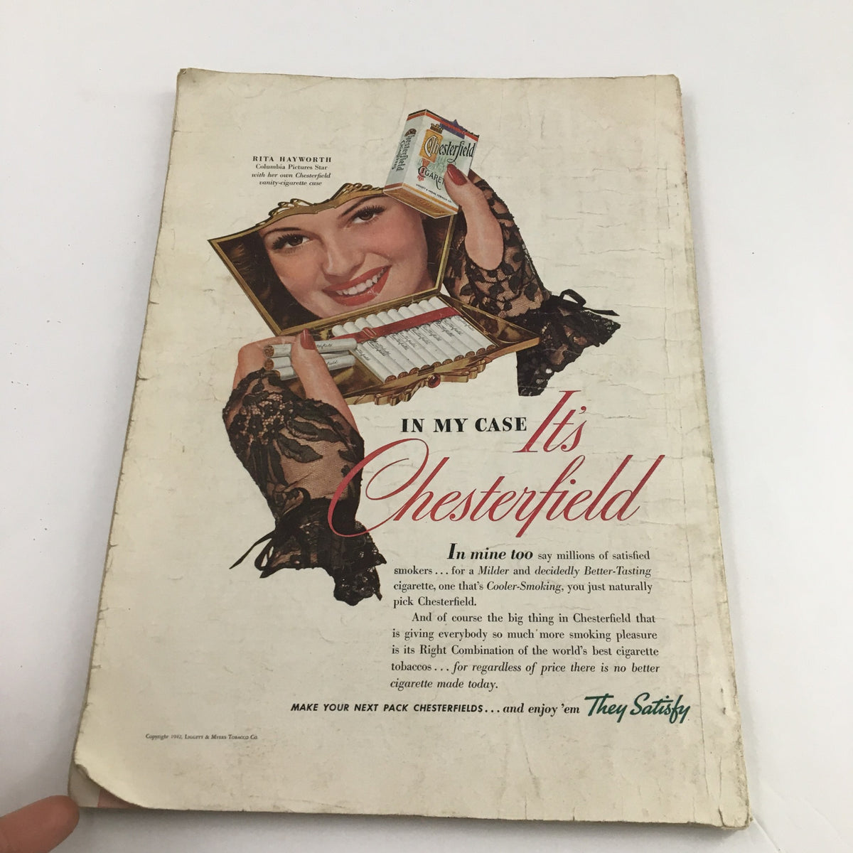 Vintage advertisement from The American Magazine May 1942, featuring a smiling woman promoting Chesterfield cigarettes.