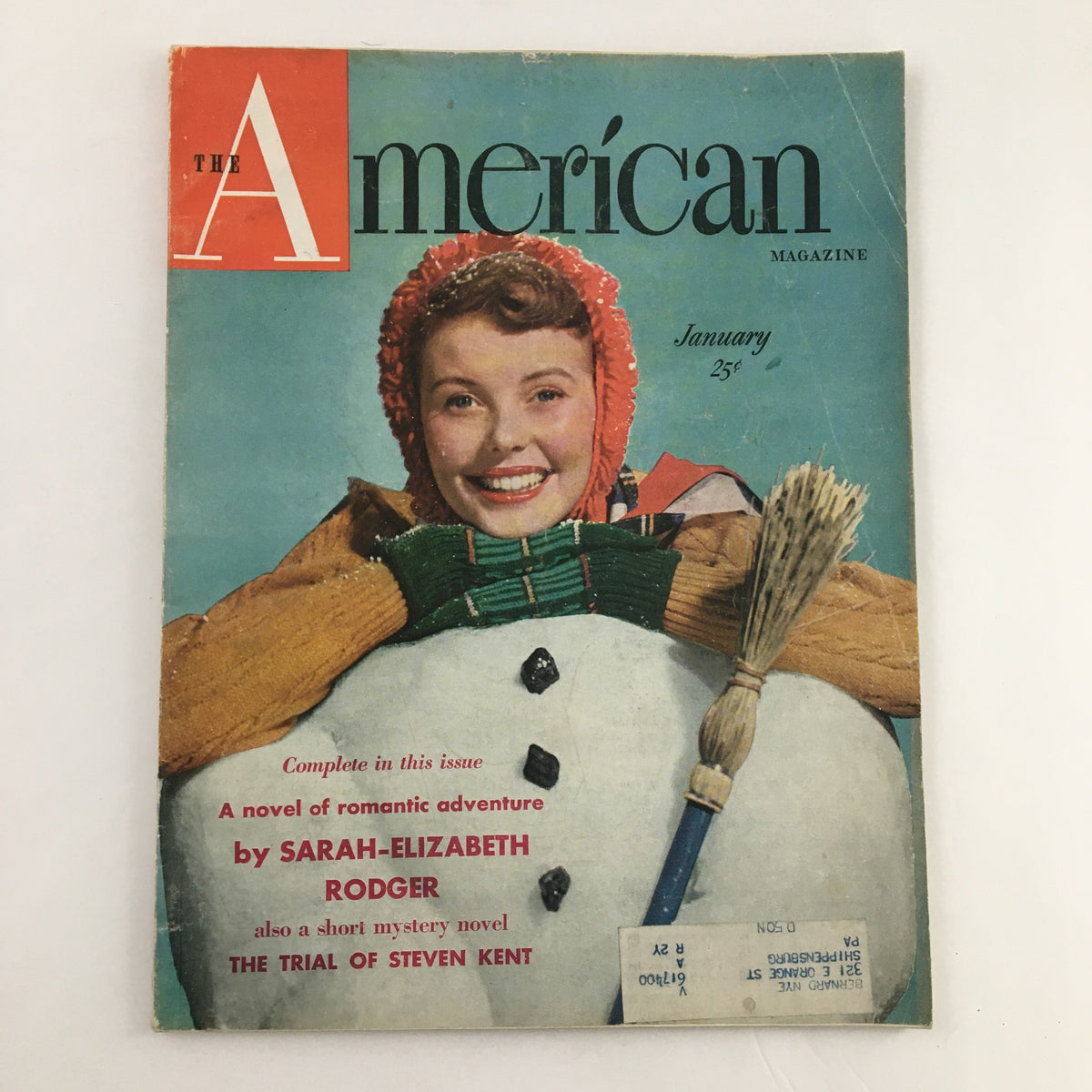 Cover of The American Magazine January 1950 featuring a smiling woman dressed for winter with a snowman, showcasing the mystery novel The Trial of Steven Kent.