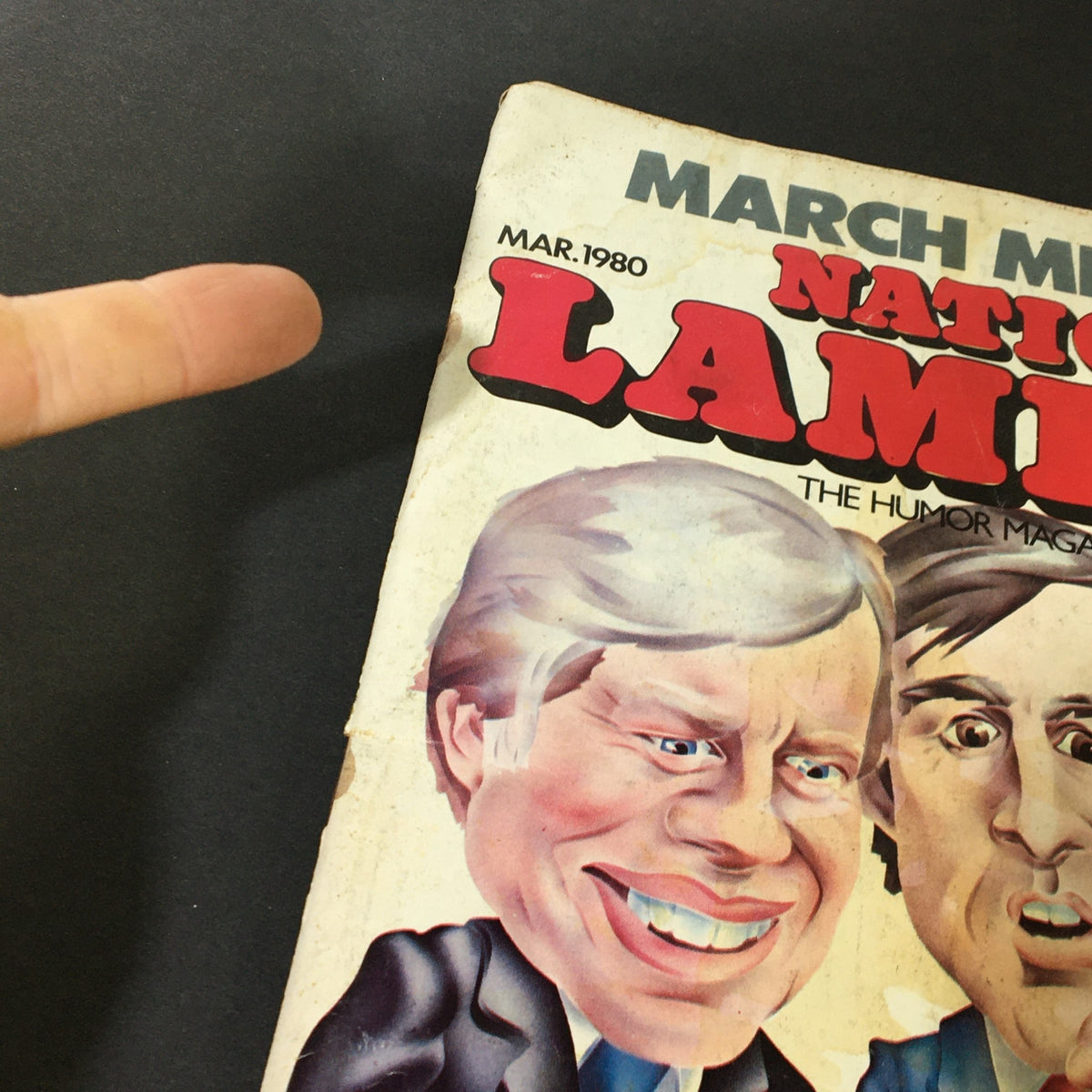 Close-up view of the National Lampoon Magazine from March 1980, showcasing the caricature detailed cover art. The image highlights the magazine's title and features significant minor wear, emphasizing its collector's item status.