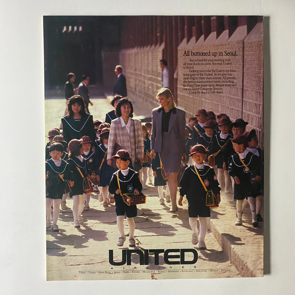 Vintage advertisement featuring United Airlines, showcasing a sophisticated scene in Seoul with children in school uniforms and women in professional attire.
