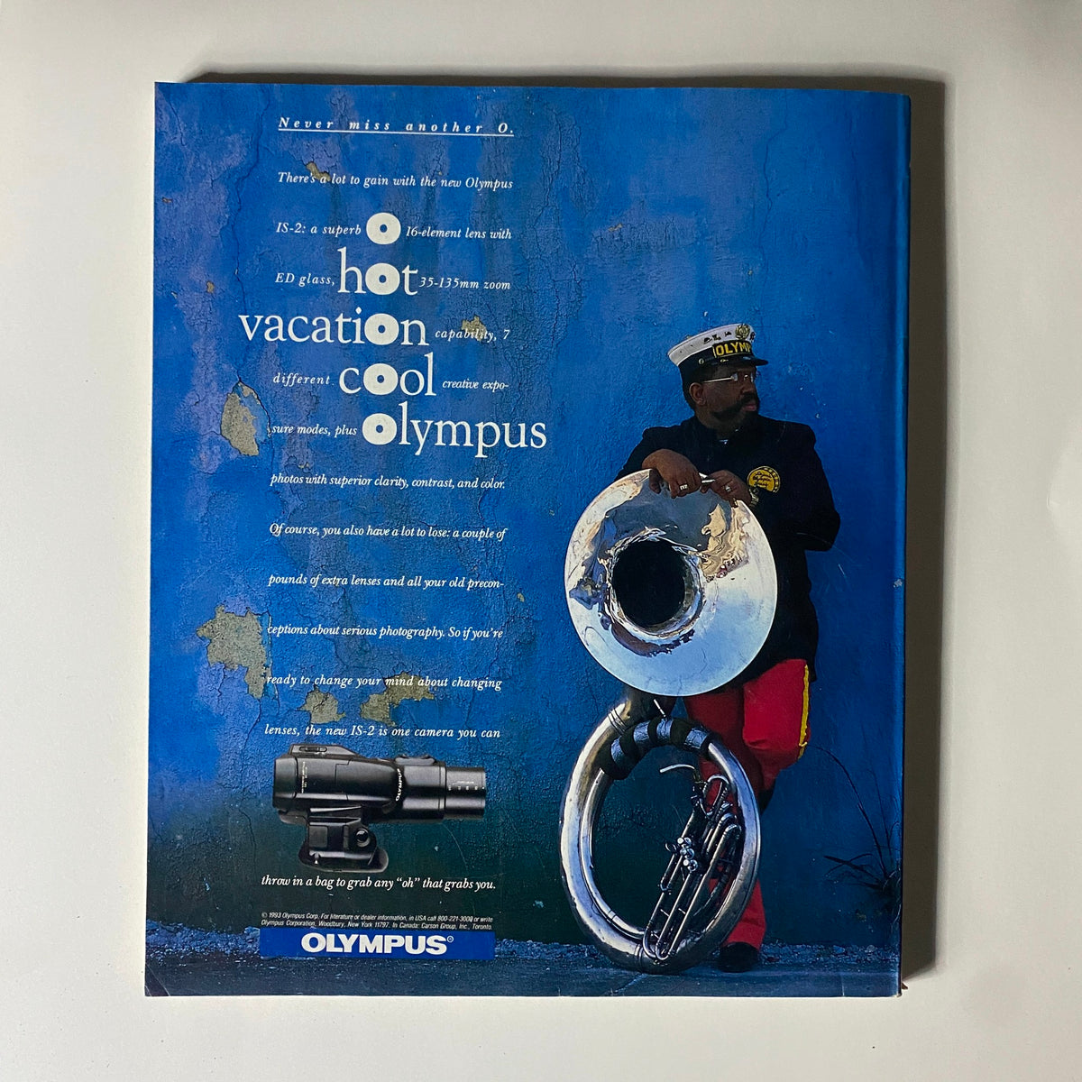 Vintage advertisement for Olympus camera showing a unique creative design, emphasizing photography features and capabilities.