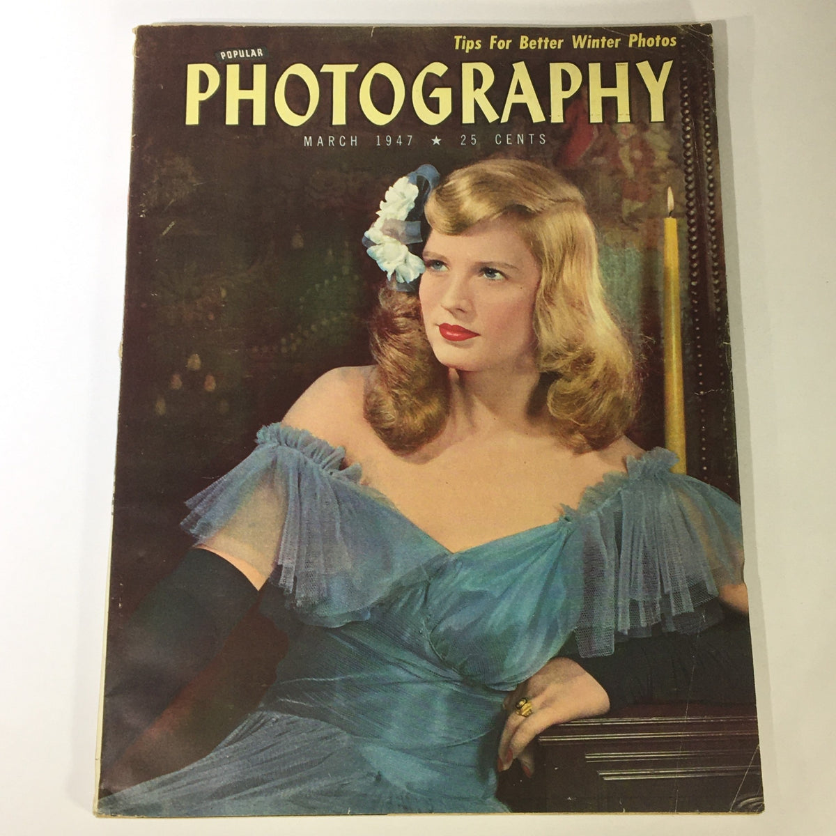 Cover of Popular Photography Magazine from March 1947 featuring tips for better winter photos, showcasing a woman in a blue dress with a flower in her hair.
