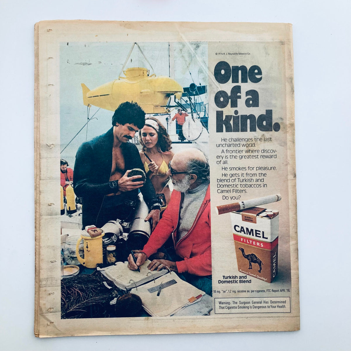 Advertisement layout from the VTG Rolling Stone Magazine January 13, 1977, issue No. 230 promoting Camel cigarettes with a slogan 'One of a Kind'. The image features individuals near a diving site, emphasizing the adventurous lifestyle of the 1970s.