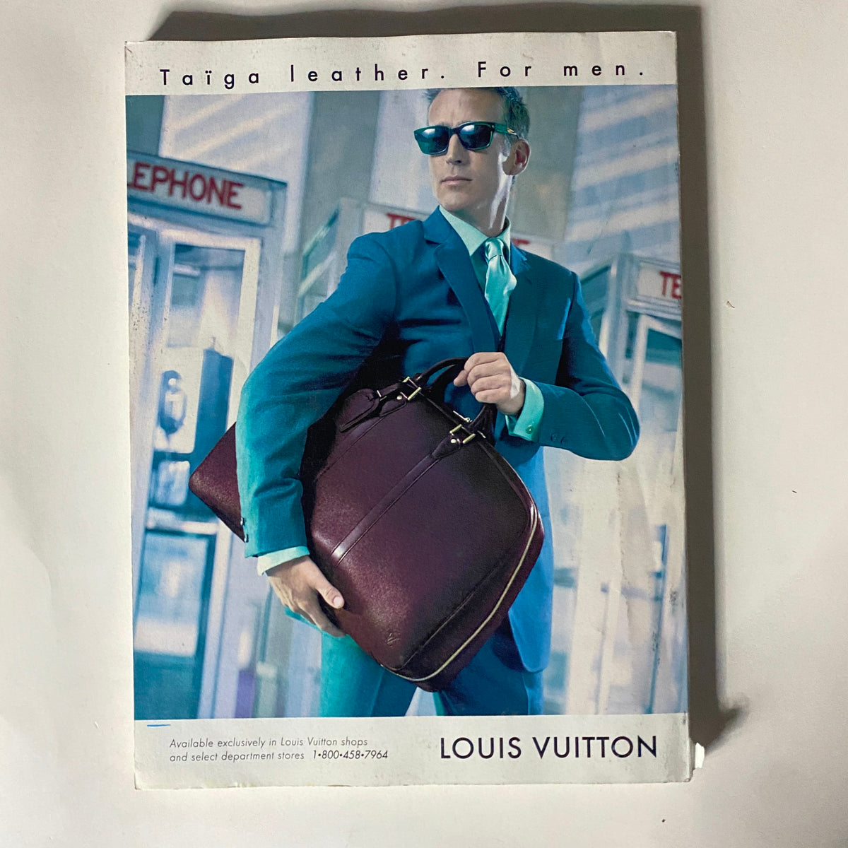 Cover page of a Louis Vuitton advertisement featuring a man in a blue suit holding a leather bag, accompanied by the text 'Taiga leather. For men.'