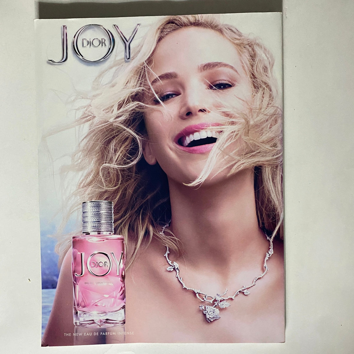 Vogue Magazine October 2019 Olivia Colman Cover displaying a luxurious Dior Joy perfume advertisement with a smiling model and elegant jewelry.