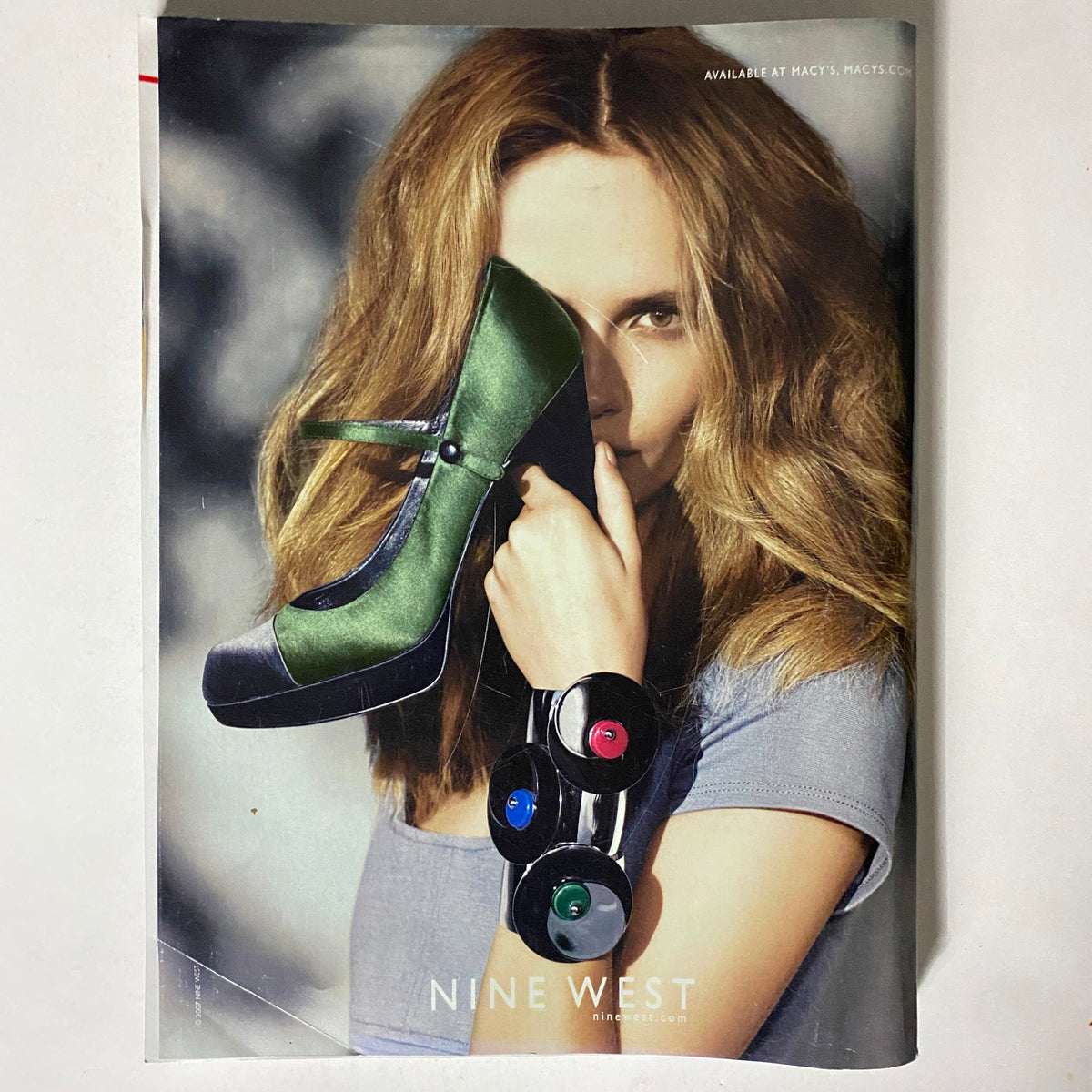 Vogue Magazine October 2007 Cover featuring a promotional image for Nine West, where a model playfully poses with a striking green and black shoe.