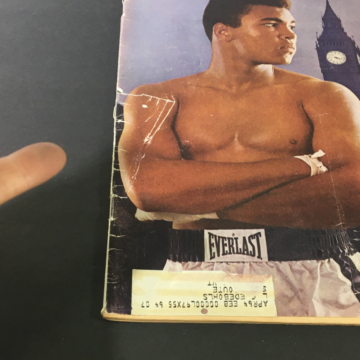 Side view of Sports Illustrated magazine dated June 10, 1963, depicting a young Cassius Clay, with his arms crossed, wearing Everlast boxing shorts. The London landmark Big Ben is visible in the background, emphasizing the theme 'Cassius Invades'.