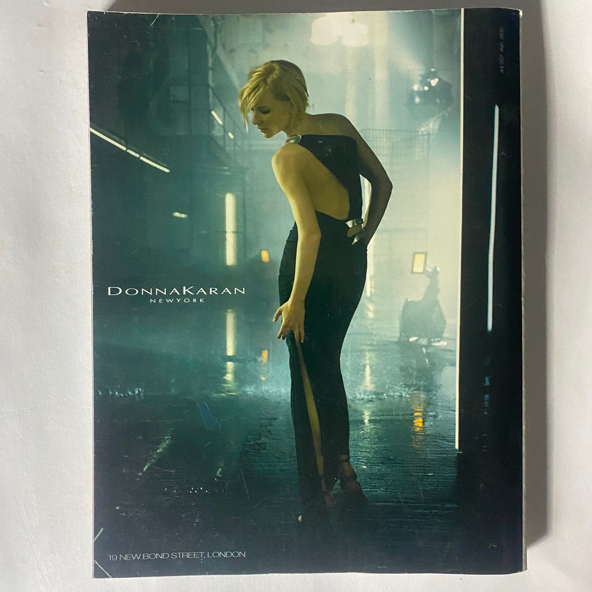 Cover page of Donna Karan advertisement from Vogue Magazine October 2003, featuring a model in a sleek black dress, projecting elegance and modern fashion.