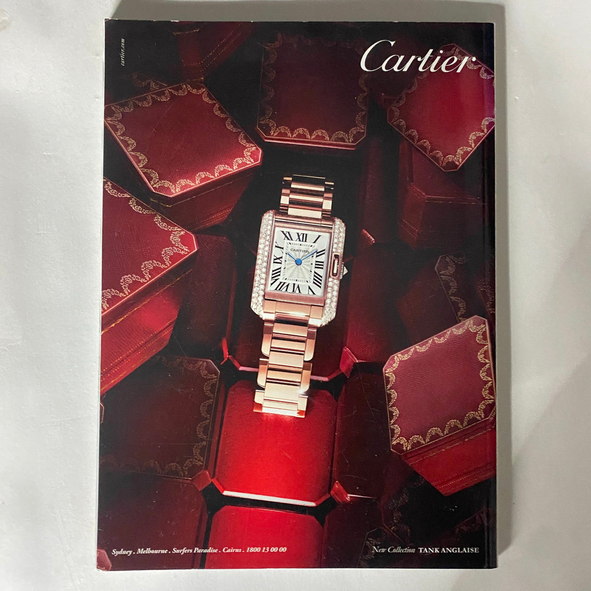 Cover of the Cartier magazine featuring an elegant watch displayed on a striking red background with luxury packaging, showcasing timeless luxury and style.