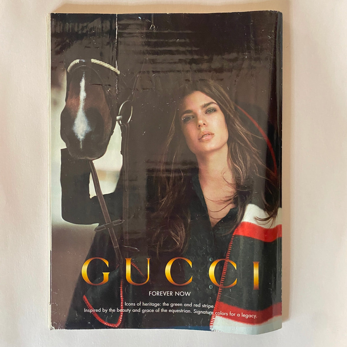 Cover of Gucci Forever Now magazine, inspired by equestrian themes, showcasing a model with a horse, highlighting luxury fashion.