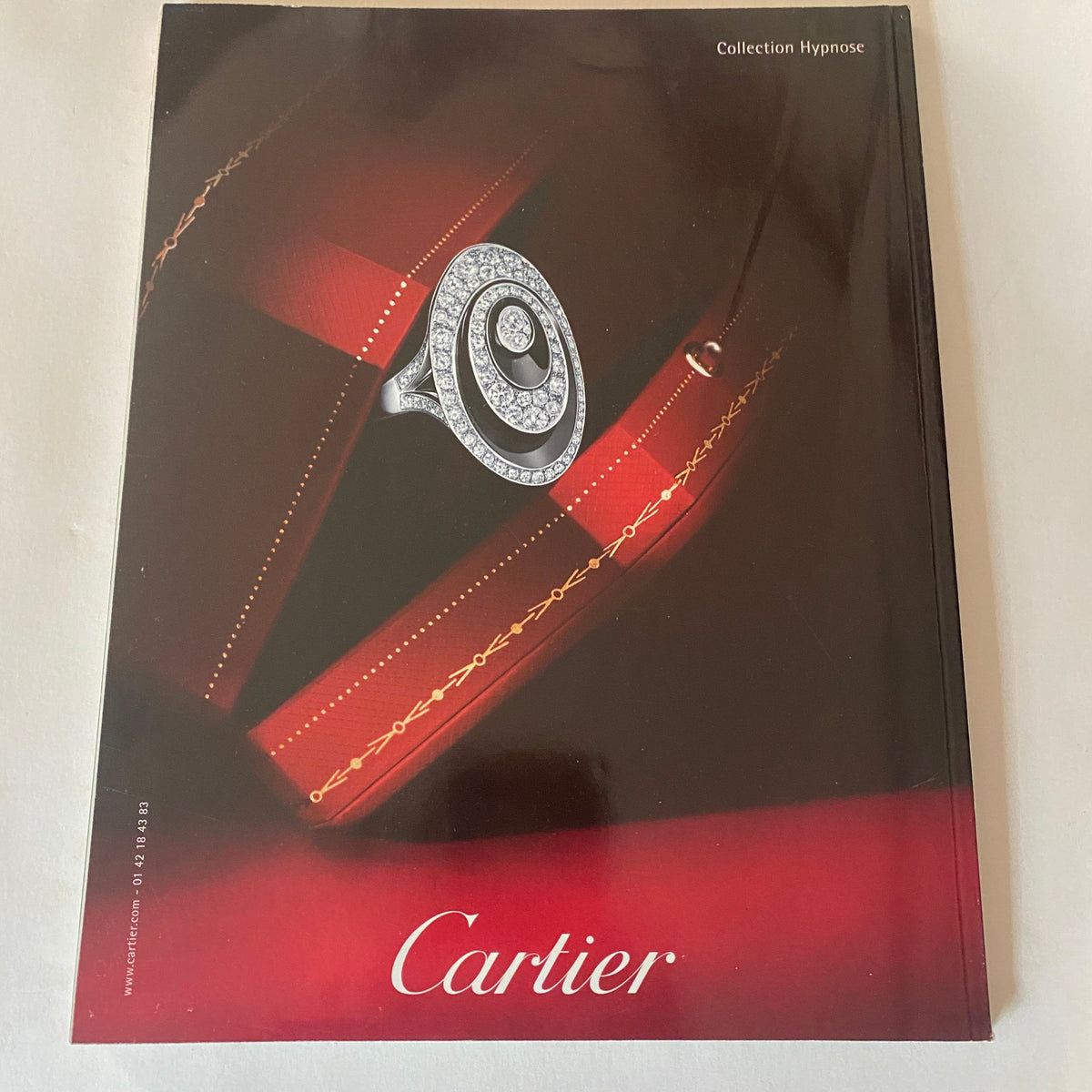 Cartier Collection Hypnose magazine cover featuring a spiral diamond ring on a red velvet background, showcasing luxury jewelry and exquisite design.
